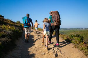 family travelers with backpacks walking track parents two kids hiking outdoors back view active lifestyle adventure tourism concept